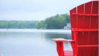 red recycled plastic adirondack chair at a lake